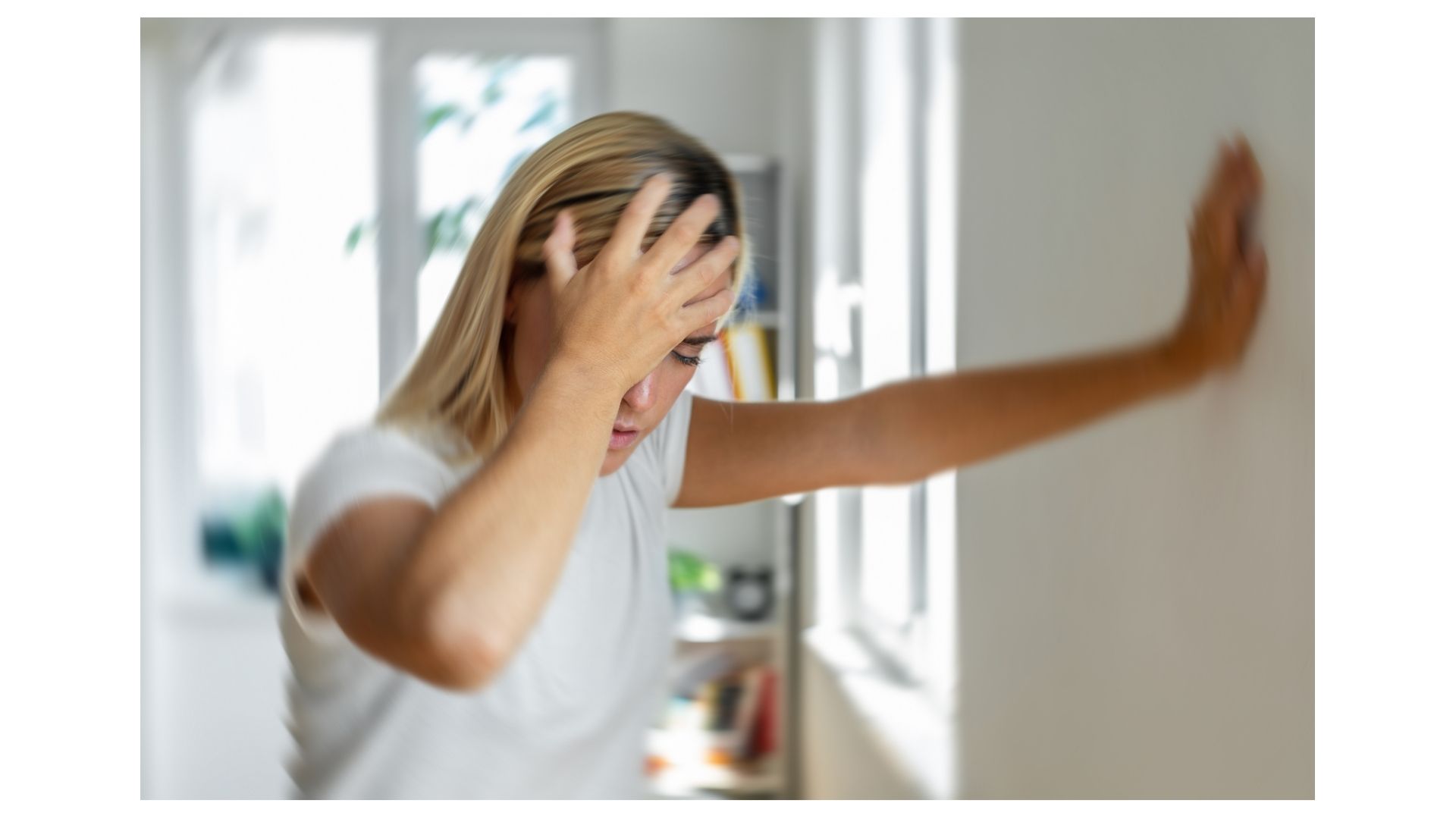Woman in North Kansas City steadying herself against a wall while experiencing vertigo and dizziness Woman in North Kansas City steadying herself against a wall while experiencing vertigo and dizziness
